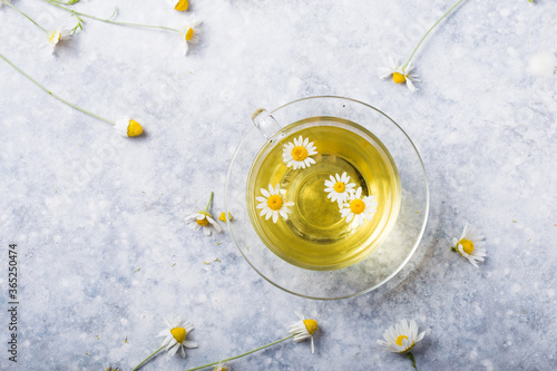 Chamomile flowers and chamomile tea in glass teacup, top view, prevention of seasona flu colds