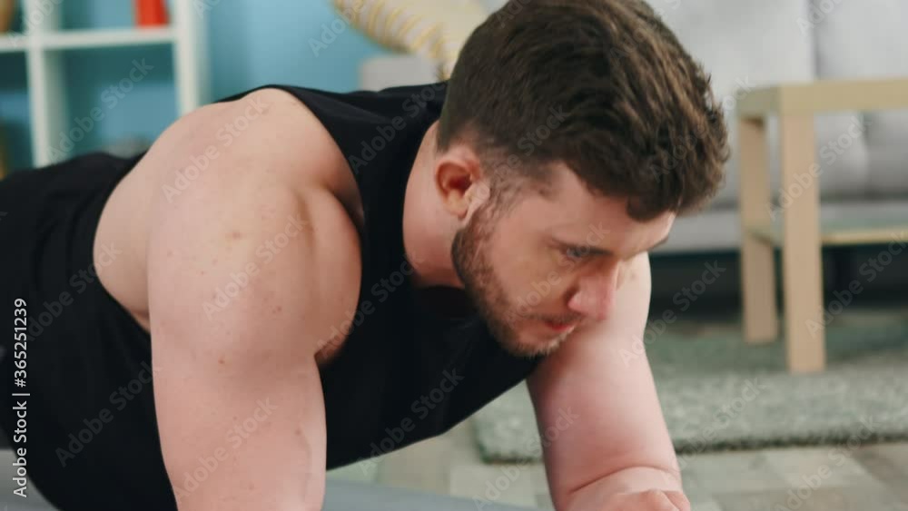 Young athletic man is standing in elbow plank, then changes to full arms plank, workouting systematically, using stopwatch on a gadget, puts efforts to strengthen his body, Slow motion. Young athletic man is standing in elbow plank, then changes to full arms plank, workouting systematically, using stopwatch on a gadget, puts efforts to strengthen his body, Slow motion.