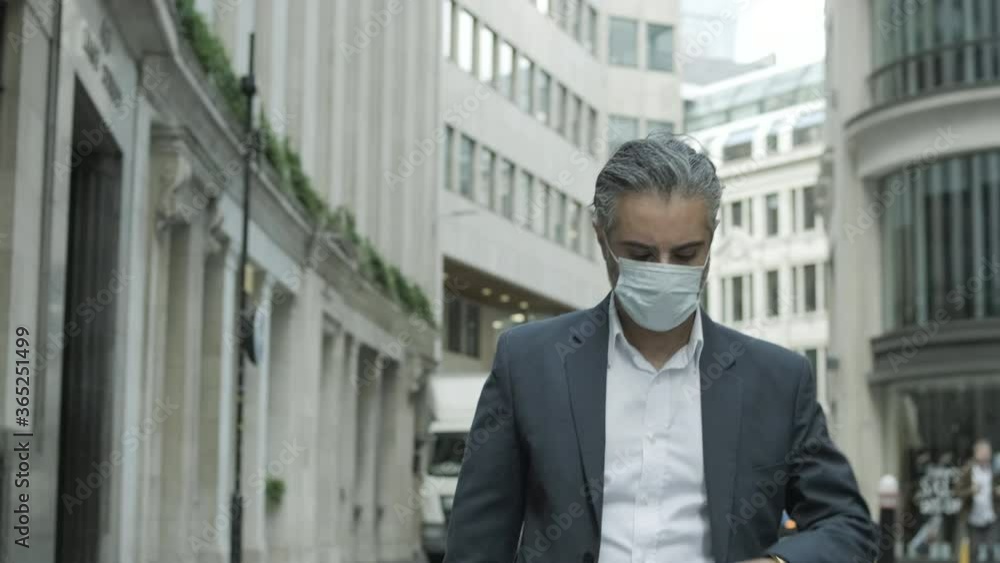 Corporate business man in suit with gray hair commuting to work wearing face mask in the city of London during Covid-19 Pandemic Corporate business man in suit with gray hair commuting to work wearing face mask in the city of London during Covid-19 Pandemic