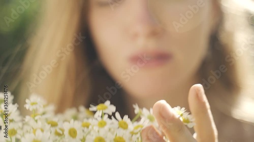 Young beautiful girl holds a bouquet of flowers of daisies in sunny weather, closeup view