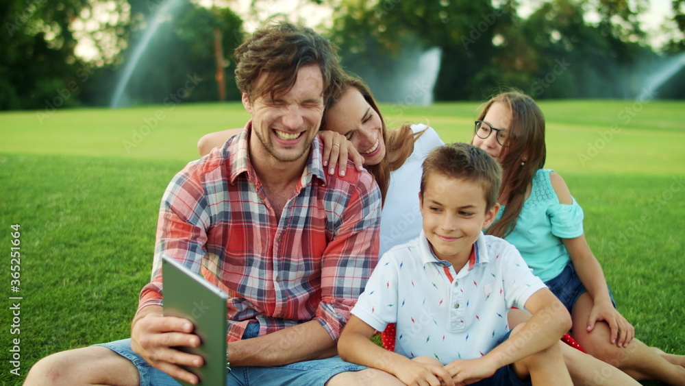 Family calling on web camera with tablet outdoors. Children and parents with pad