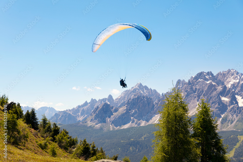 two people use paragliding, and fly in the mountains of the dolomite alps two people use paragliding, and fly in the mountains of the dolomite alps
