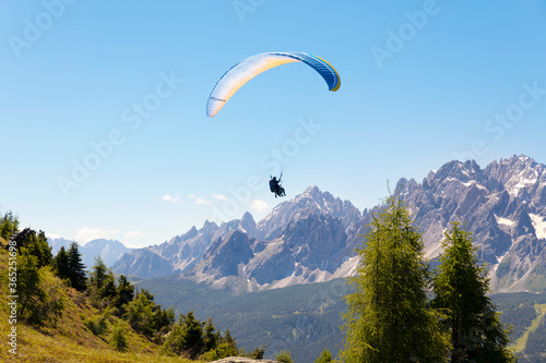two people use paragliding, and fly in the mountains of the dolomite alps