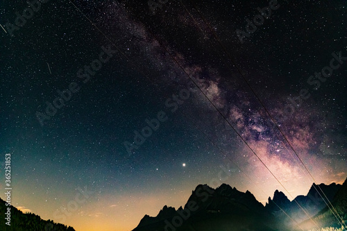 Night photography of the Milky Way and the starry sky, over the Italian Alps mountains. (Dolomites). Shooting stars, striking colors, silhouette of the peaks