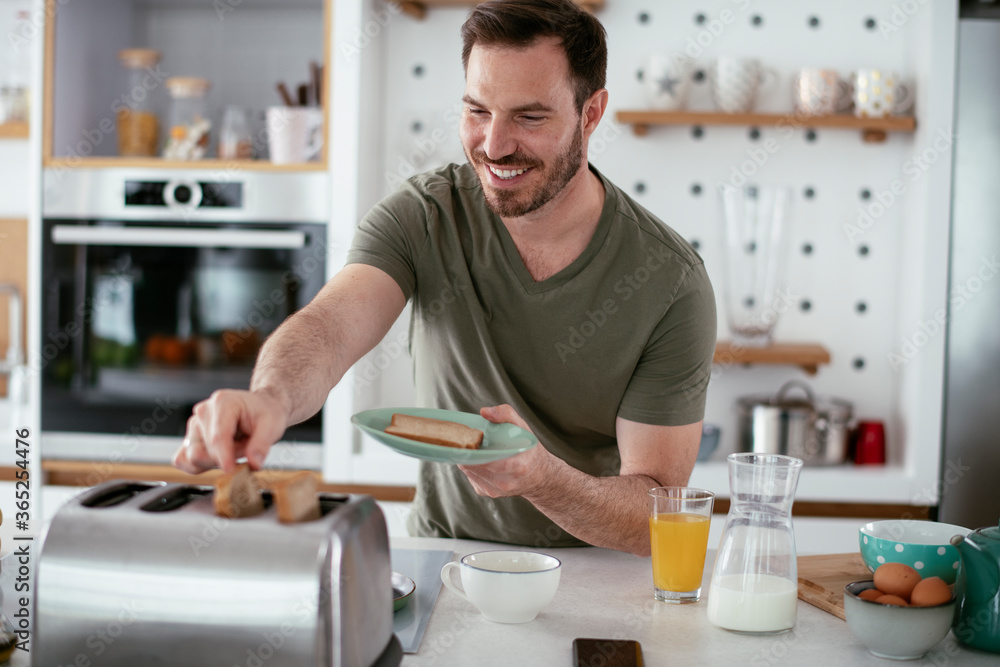 Handsome man preparing breakfast at home. Young man drinking coffee in kitchen. Handsome man preparing breakfast at home. Young man drinking coffee in kitchen.