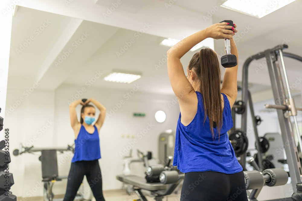 Obraz premium Woman training with medical facemask in gym. Female breathes deeply stock photo