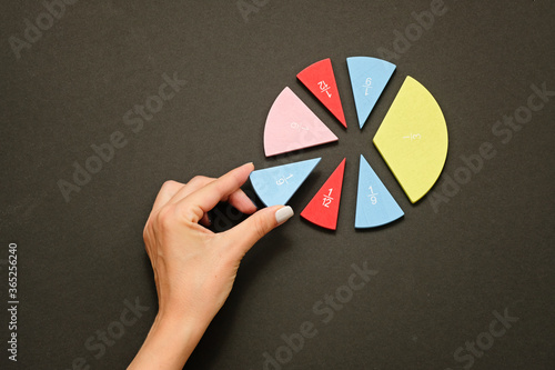 Colorful fraction circles arranged into a circle graph and hand, black background. photo