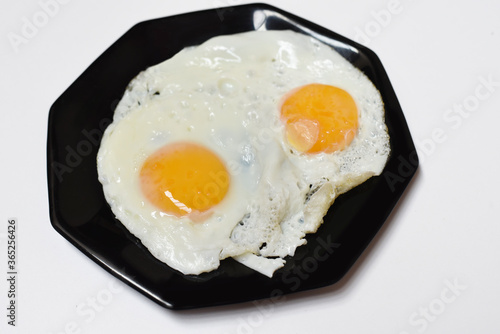 Close up of two delicious fried eggs on a plate ready to eat isolated on a white background