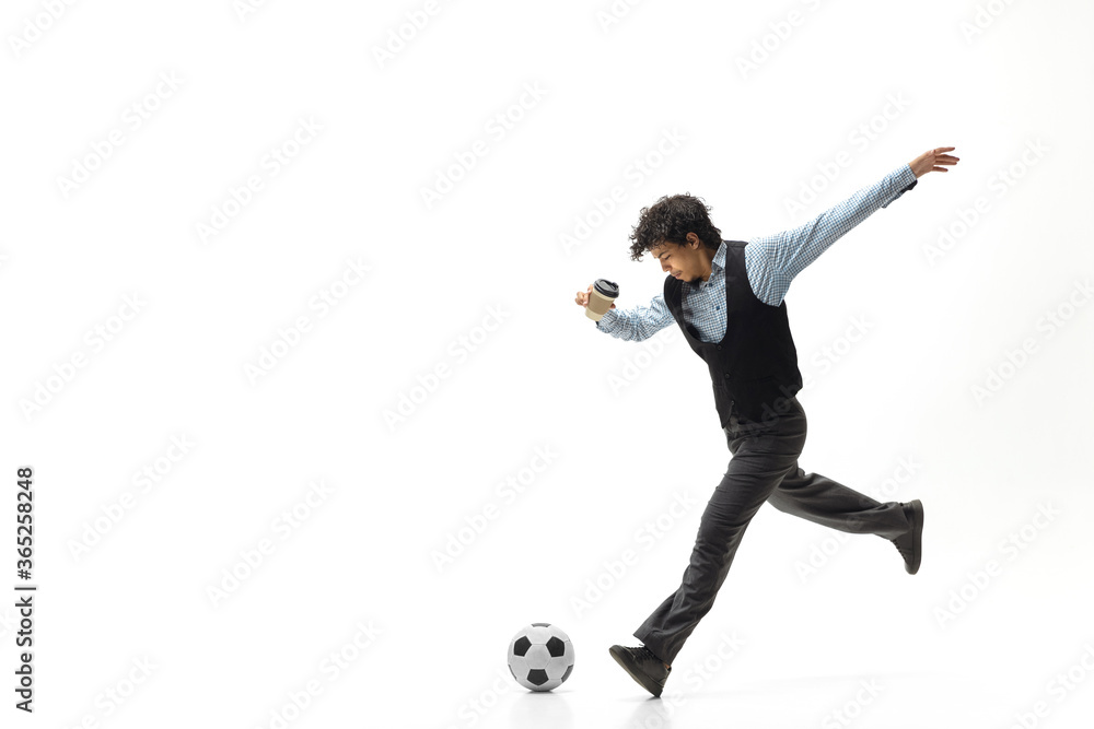 Man in office clothes playing football or soccer with ball on white background like professional player. Unusual look for businessman in motion, action kicking ball. Sport, healthy lifestyle