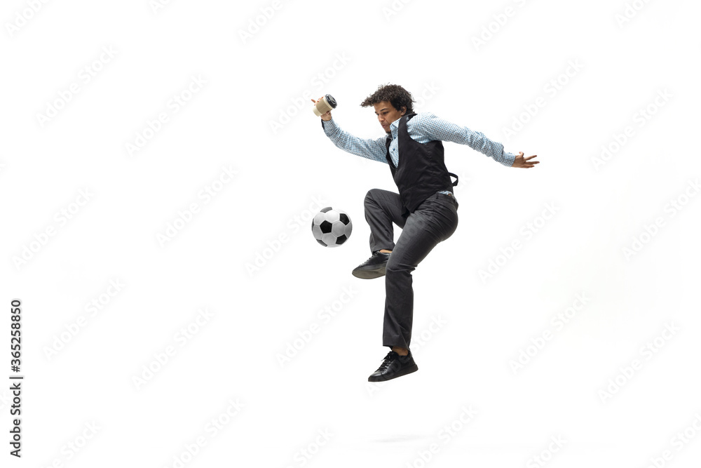 Man in office clothes playing football or soccer with ball on white background like professional player. Unusual look for businessman in jump kicking ball. Sport, healthy lifestyle, creativity. Man in office clothes playing football or soccer with ball on white background like professional player. Unusual look for businessman in jump kicking ball. Sport, healthy lifestyle, creativity.