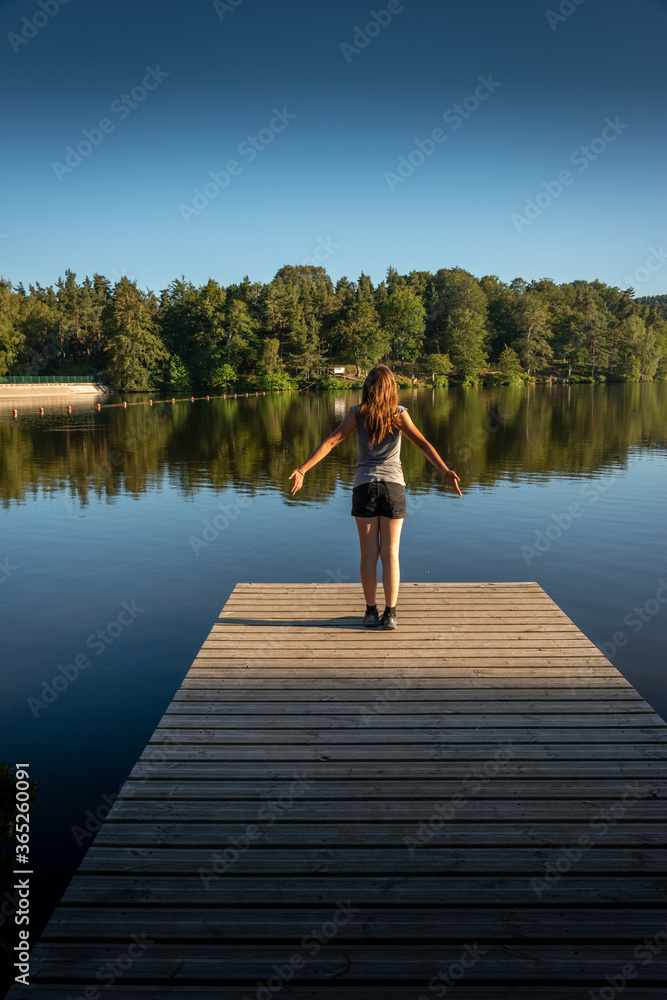 young woman stretching at the end of a wooden jetty in the evening ,concept free spirit.