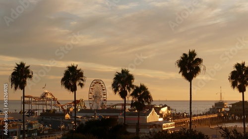 Classic ferris wheel, amusement park on pier in Santa Monica pacific ocean beach resort. Summertime California aesthetic, iconic view, symbol of Los Angeles, CA USA. Sunset golden sky and attractions photo