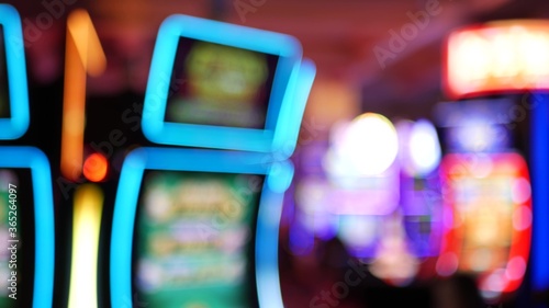 Defocused slot machines glow in casino on fabulous Las Vegas Strip, USA. Blurred gambling jackpot slots in hotel near Fremont street. Illuminated neon fruit machine for risk money playing and betting