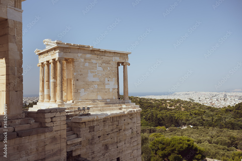 The temple of Nike on the Acropolis in Athens in Greece without people in the sunlight and blue sky with the city of Athens in background