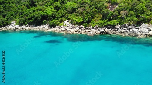 Calm sea near tropical volcanic island. Drone view of peaceful water of blue sea near stony shore and green jungle of volcanic Koh Tao Island on sunny day in Thailand.