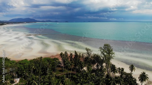Unusual coast of white sand. Breathtaking landscape of sandy wavy seaside. Paradise islands in Asia. Drone view, natural idyllic scene, coconut palms on the beach. Thunderstorm in the tropics.