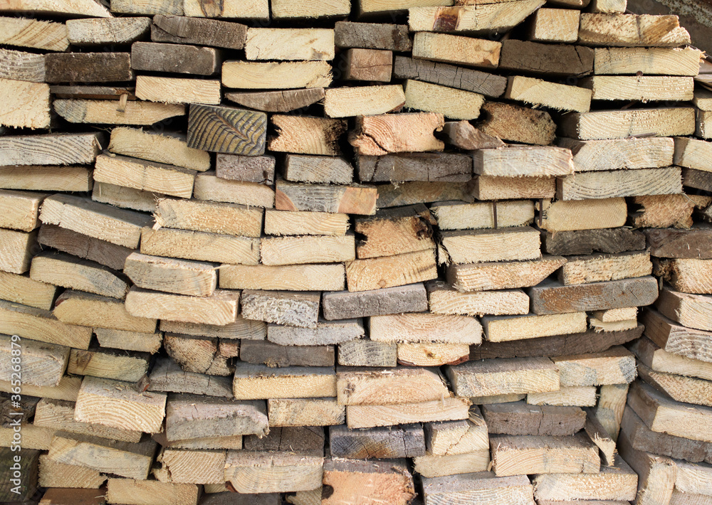 A large pile of cut wooden boards arranged along a wall A large pile of cut wooden boards arranged along a wall