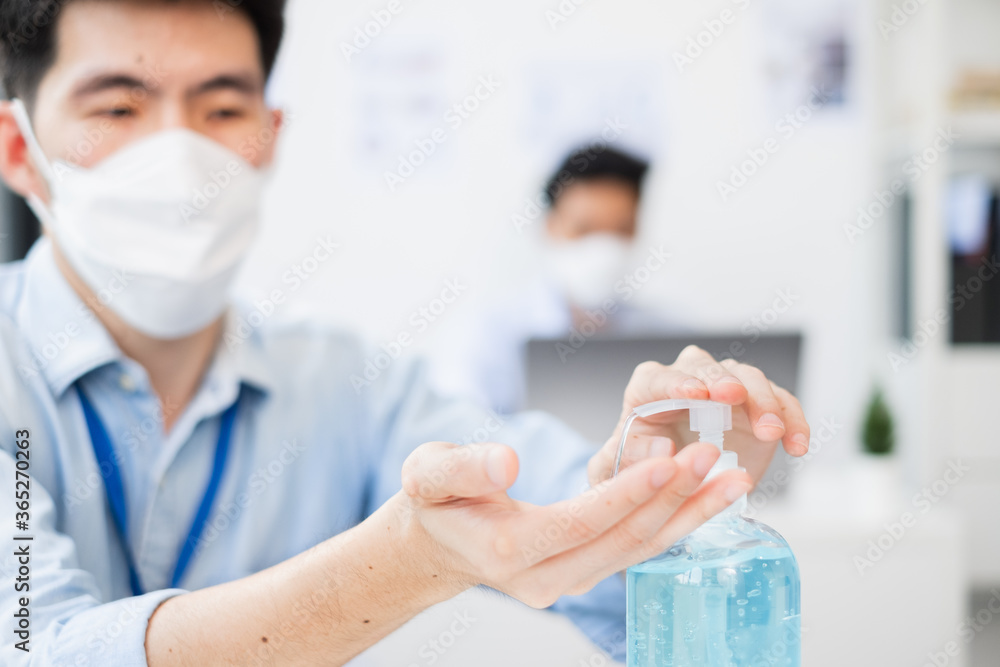 Asian business people wear protective face mask and wash hands with sanitizer in working office to protect infection of coronavirus covid-19, business reopen with new normal and social distancing Asian business people wear protective face mask and wash hands with sanitizer in working office to protect infection of coronavirus covid-19, business reopen with new normal and social distancing