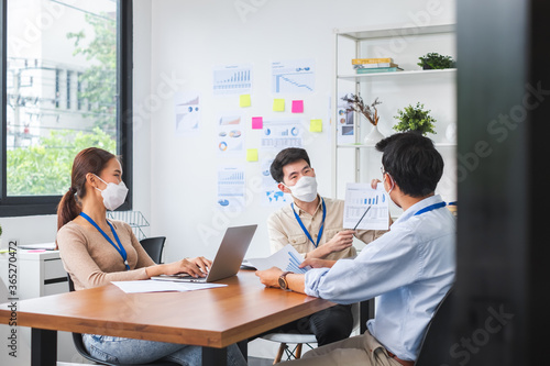 Asian business people wear face mask working and meeting in office to protect infection of coronavirus covid-19, reopen business with new normal and social distancing concept