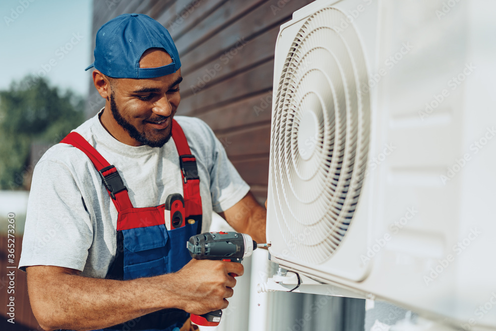 Foto de Repairman in uniform installing the outside unit of air