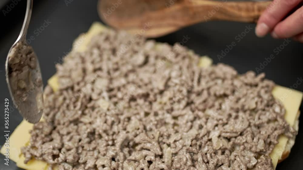 Adding fried ground beef on bread rolls in slow motion. Concept of