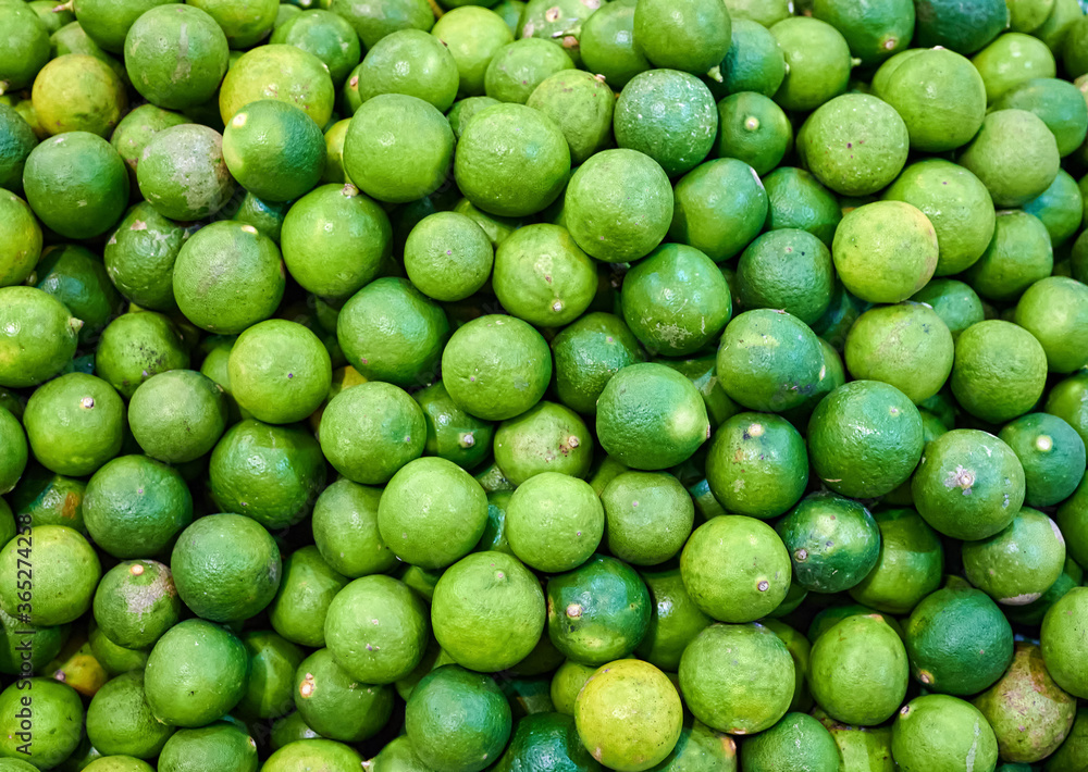 Closeup photo of lime pile on shelf. Texture background of fresh ingredient in gourmet market. Closeup photo of lime pile on shelf. Texture background of fresh ingredient in gourmet market.