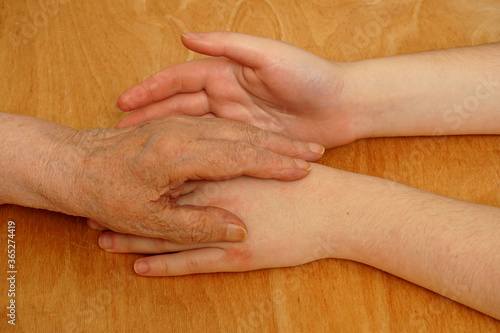  The hand of an elderly woman lies on the girl's hand.