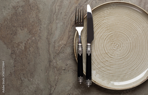 Plate, knife and fork on stone background