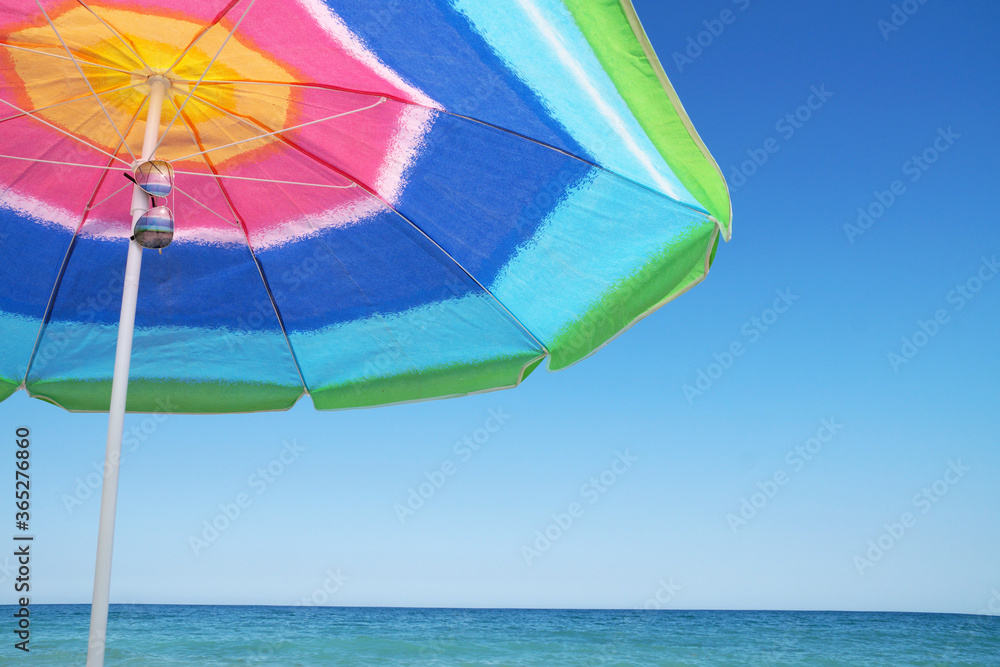beach umbrella and sunglasses against the sea horizon and clear sky, copy space.