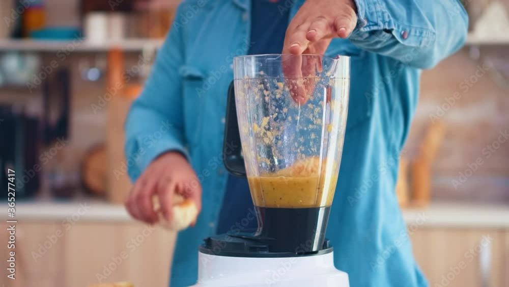 Man mixing fruits with blender for tasty smoothie in kitchen. Cheerful family making together organic healthy fresh nutritious tasty juice for breakfast from fresh fruits while on a diet. Man mixing fruits with blender for tasty smoothie in kitchen. Cheerful family making together organic healthy fresh nutritious tasty juice for breakfast from fresh fruits while on a diet.