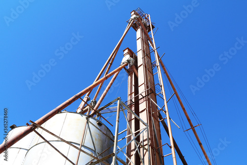 angle view of an agricultural feed grain and corn elevator silo building against a blue sky in rural heartland america perfect for industry farming and commercial agriculture marketing
