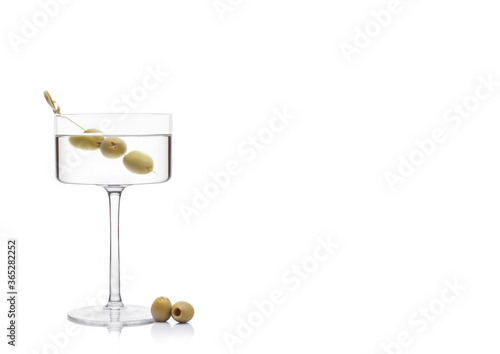 Vodka martini gin cocktail in modern glass with olives on bamboo stickwith fresh green olives on white background with reflection. photo