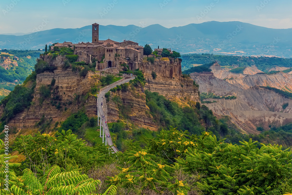 A view towards the entrance bridge for the hill top settlement of Civita di Bagnoregio in Lazio, Italy in summer