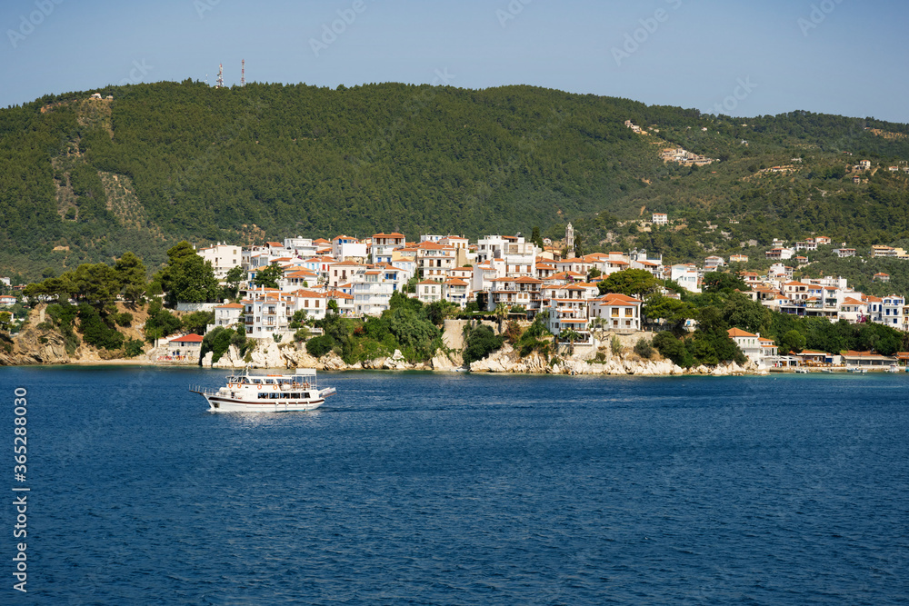 The historical town on Skiathos island seen from the boat when entering the harbour in summer light.