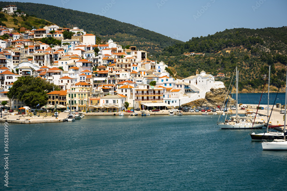 The historical town on Skopelos island seen from the boat when entering the harbor in summer light.