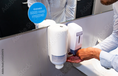 Anti-Covid measures. COVID-19: guidance for the workplace and office. Prevention and Mitigation of Coronavirus, man sanitizing hands in the toilet photo