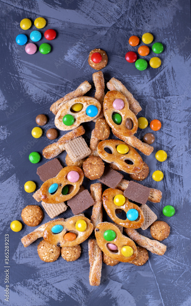 Christmas tree made of different cookies, waffles and candies. Top view. Creative festive background