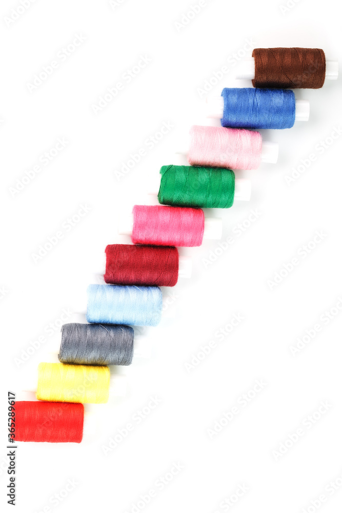 Sewing threads of different colors on reels on a white background. Free space, close-up. Isolate Sewing threads of different colors on reels on a white background. Free space, close-up. Isolate