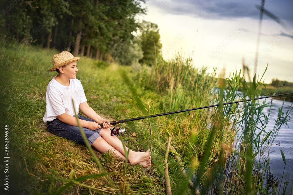 Young teen boy holding fishing rod and looking in river Young teen boy holding fishing rod and looking in river