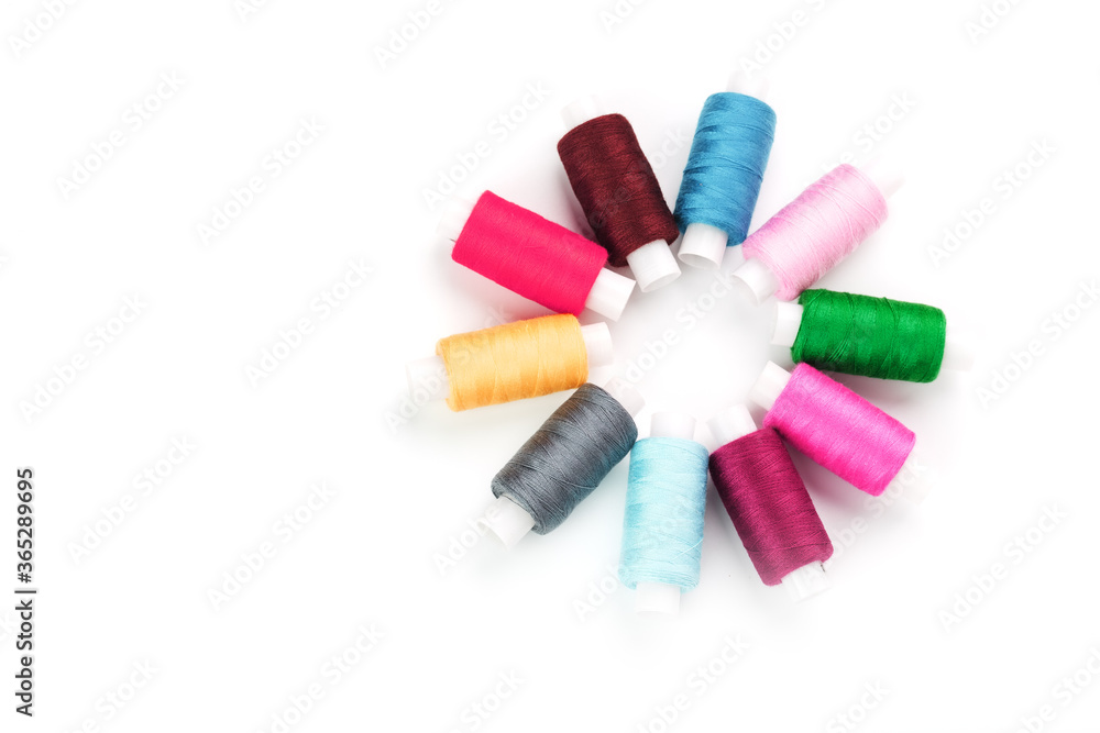 Sewing threads of different colors on reels on a white background in a circle. Sewing threads of different colors on reels on a white background in a circle.