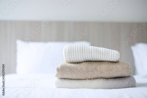 Stack of beige wool Sweaters on bed in luxury hotel or resort or home. Relax, autumn or winter clothes, laundry and vacation concepts © Jo Panuwat D
