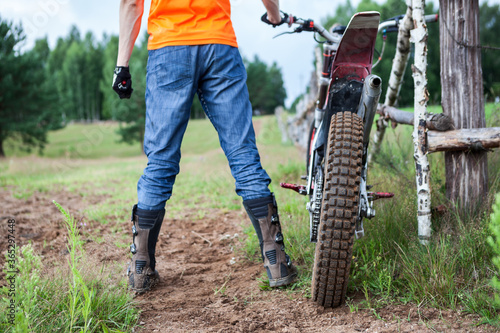 Motorcyclist is ready for off road riding on off-road motorcycle with cross-country tyres, rear view photo