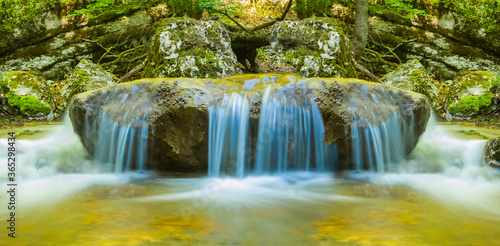 closeup smal waterfall on a mountain river rushing through a canyon