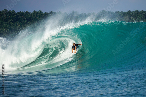 Surfer on perfect blue big tube wave, empty line up, perfect for surfing, clean water, Indian Ocean in Mentawai islands