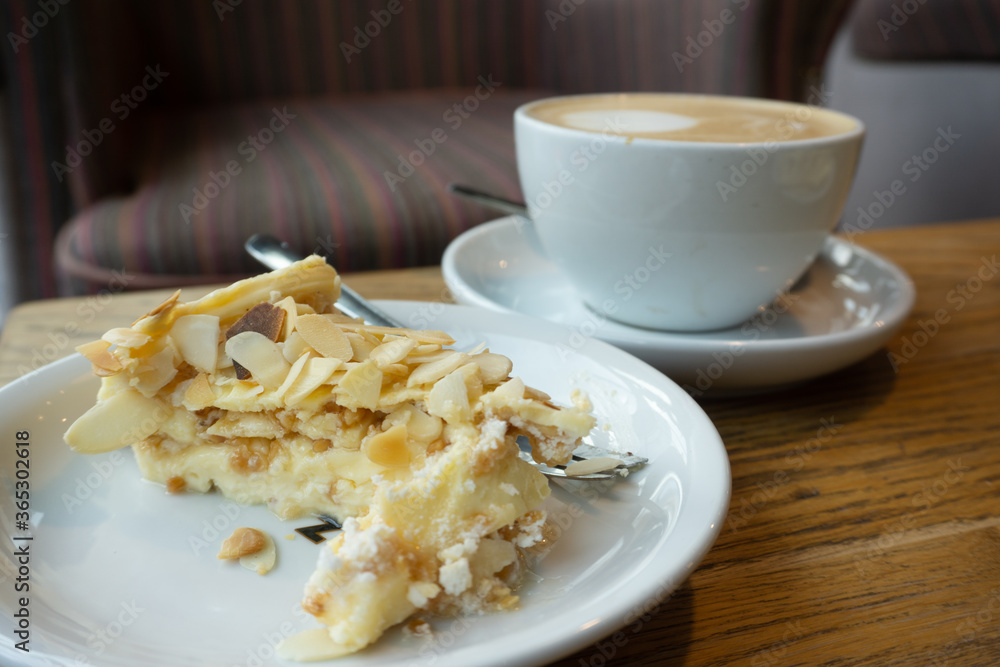 A cup of coffee and cake with cream and almond A cup of coffee and cake with cream and almond
