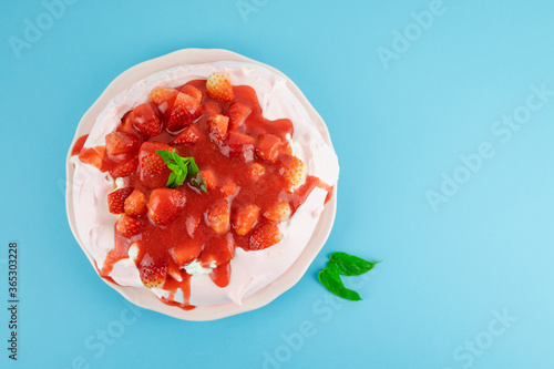 Pavlova with red fruits on a blue background. Copy space. Pastry concept.