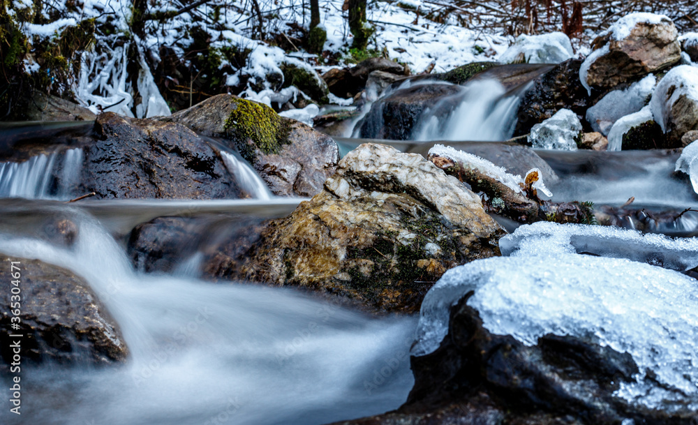 semi frozen small waterfall in a stream in the mountains in deep winter with ice semi frozen small waterfall in a stream in the mountains in deep winter with ice