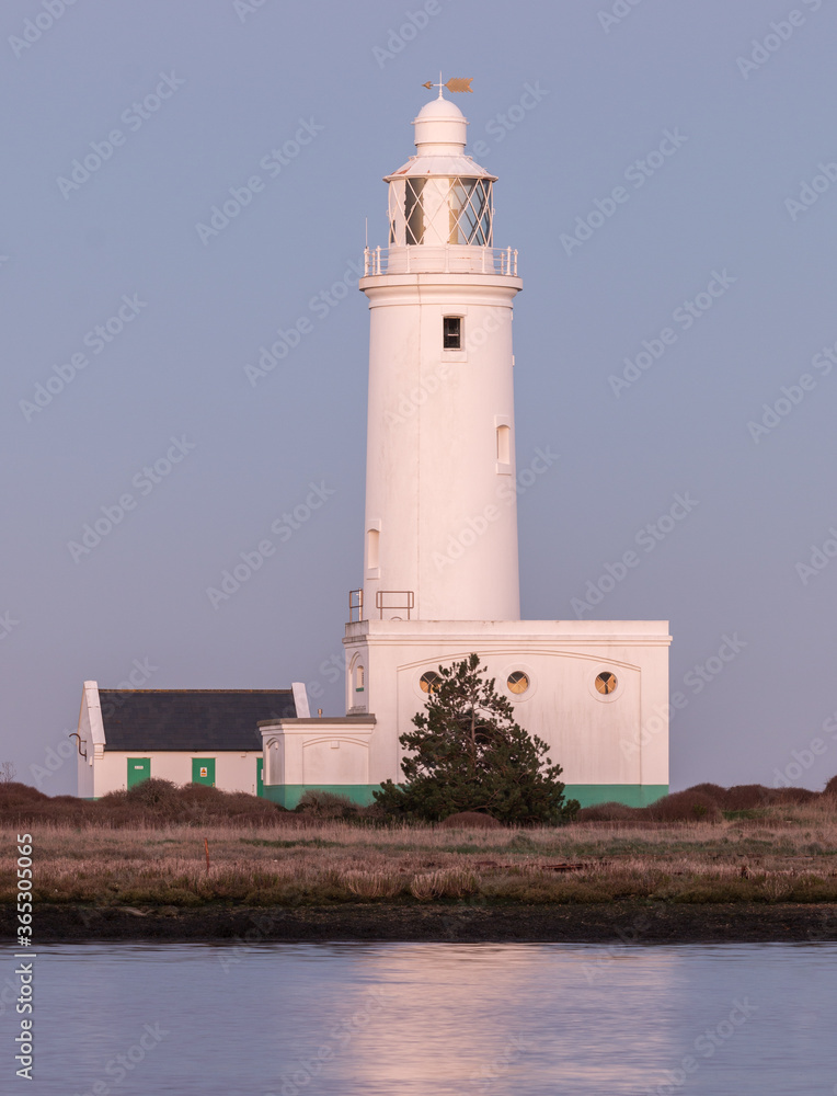 The lighthouse at the end of Hurst Spit in the village of Milford-on-Sea, Hampshire, UK. Evening light gives a subtle hue to the white paint