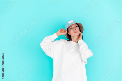 Sports girl in white logo sweatshirt. Woman in denim hat