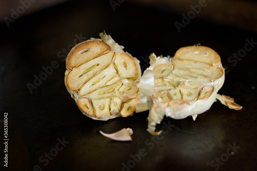 Roasted garlic halves on black background